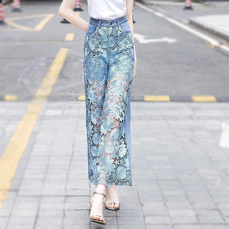 Model walking in patchwork denim draping pants for women with transparent lace panels and a modern, airy design for summer fashion.